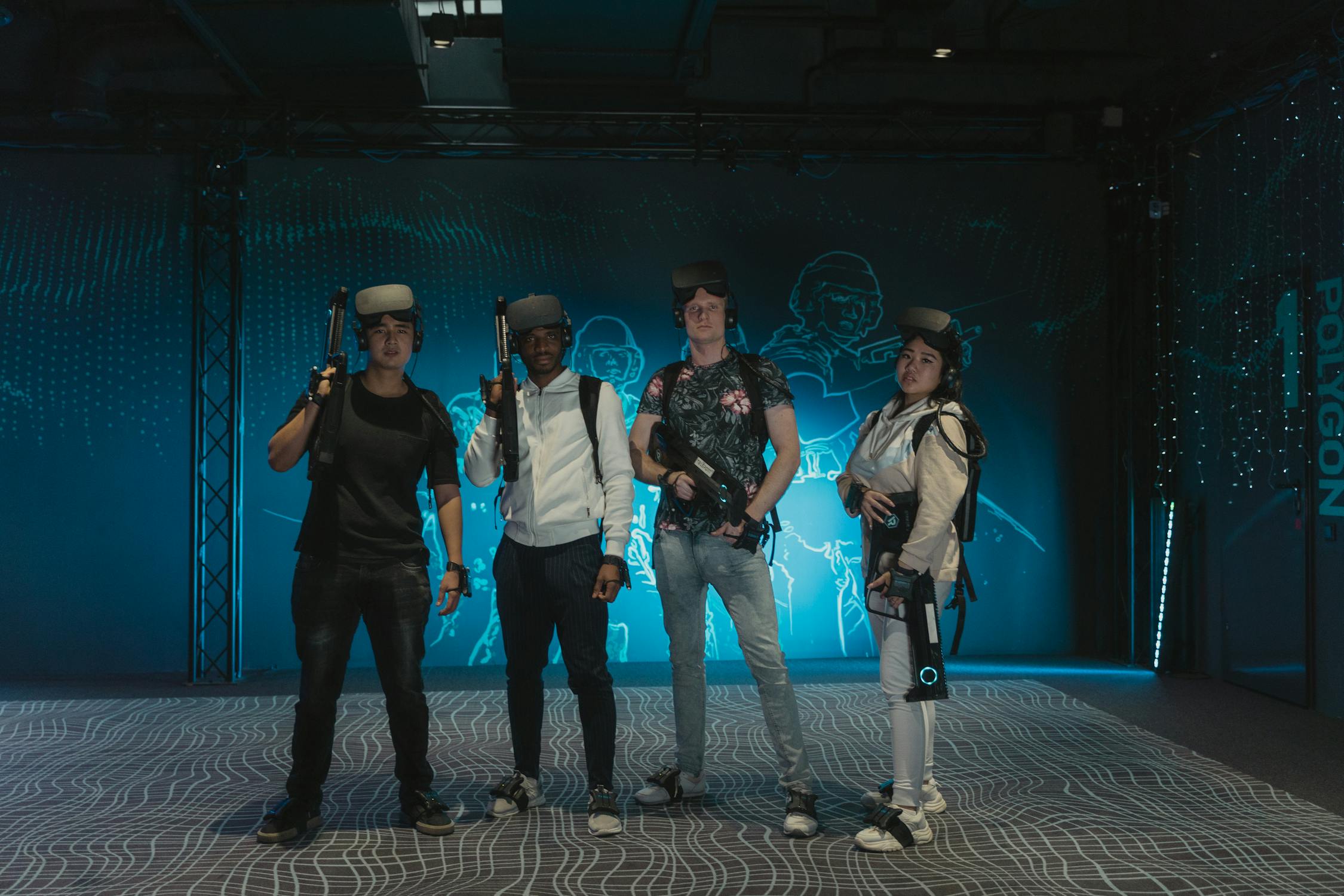 Grupo de amigos posando com headsets VR brancos e armas VR em arena de realidade virtual
